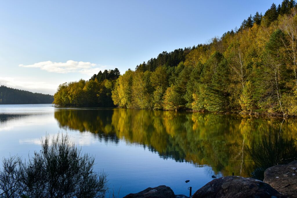 Peaceful autumn landscape of Lake Pierre-Percée with vibrant foliage reflections.